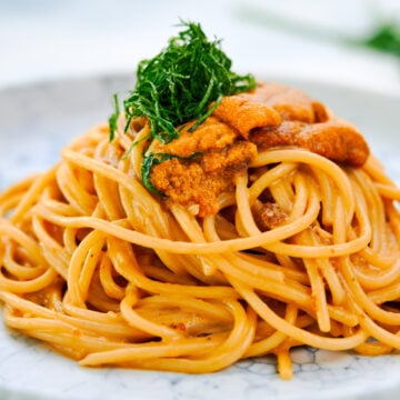 Creamy uni pasta with spaghetti, garnished with fresh uni and green shiso.