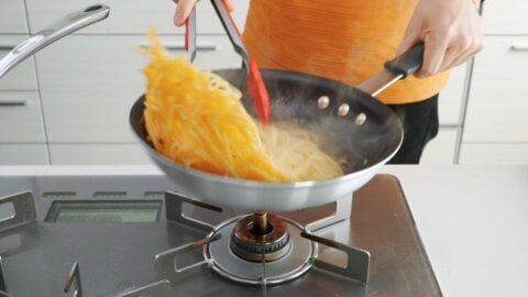 Tossing spaghetti with the olive oil and garlic.