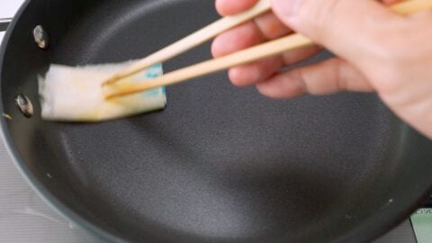 Wiping a non-stick frying pan with oiled paper towel to make Usuyaki Tamago