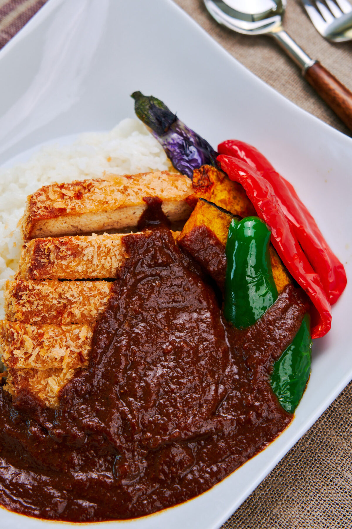 Crispy Tofu Katsu with a rich and flavorful Japanese curry sauce from scratch (vegan and vegetarian friendly). Served with a side of peppers, pumpkin and eggplant.