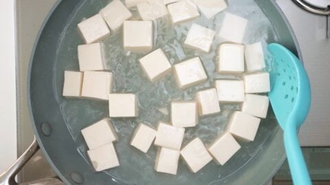 Simmering tofu in salt water to remove excess liquid.