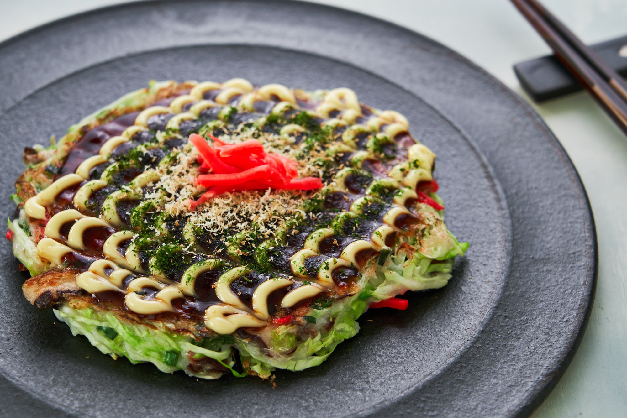 Okonomiyaki is a savory Japanese pancake that's made with a cabbage-based batter and it can be customized like a pizza with your favorite mix-ins and toppings.