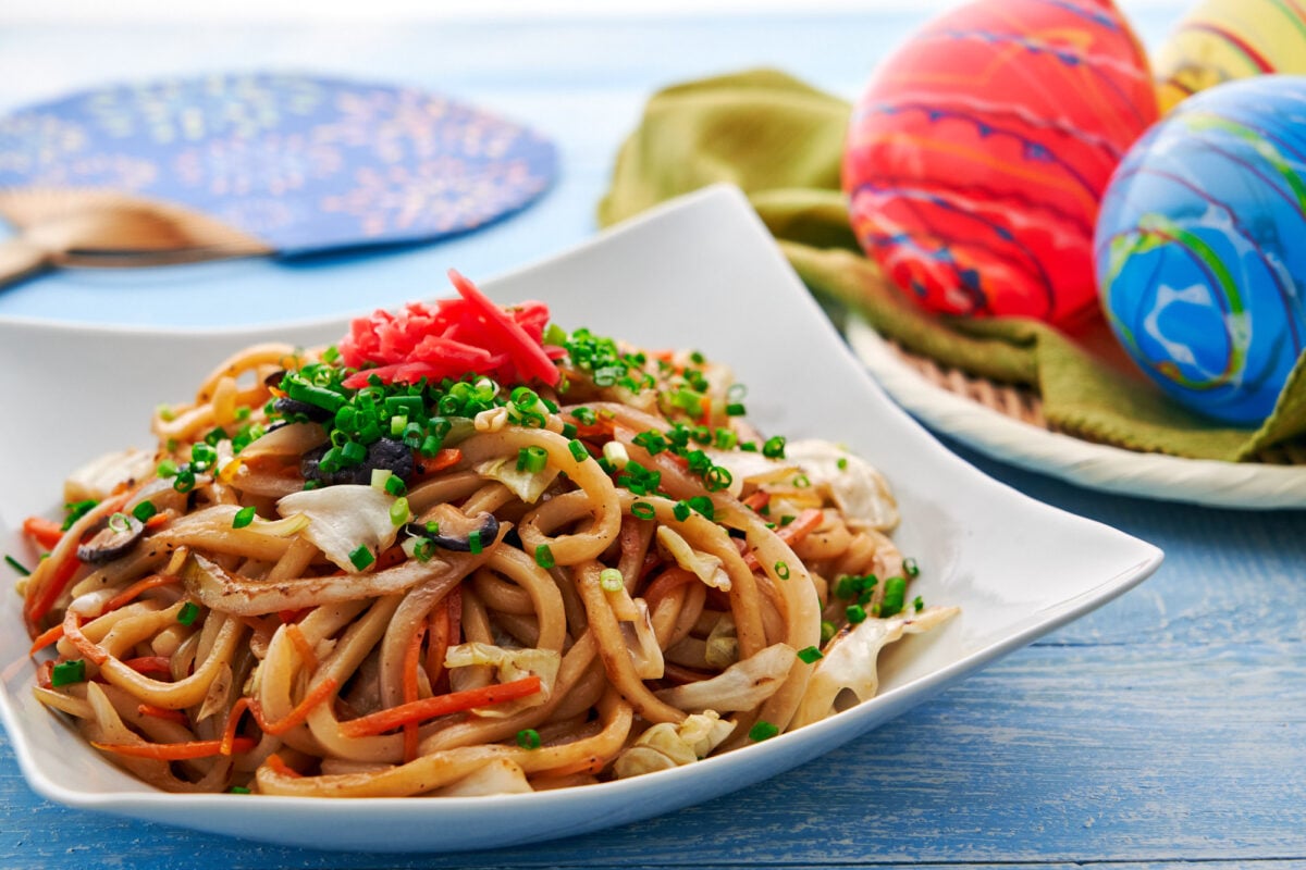 Stir-fried udon noodles with vegetables and mushrooms topped with scallions and red ginger.