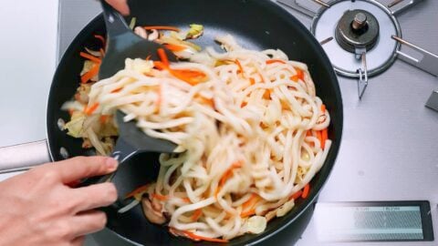 Stir-frying udon noodles with vegetables.