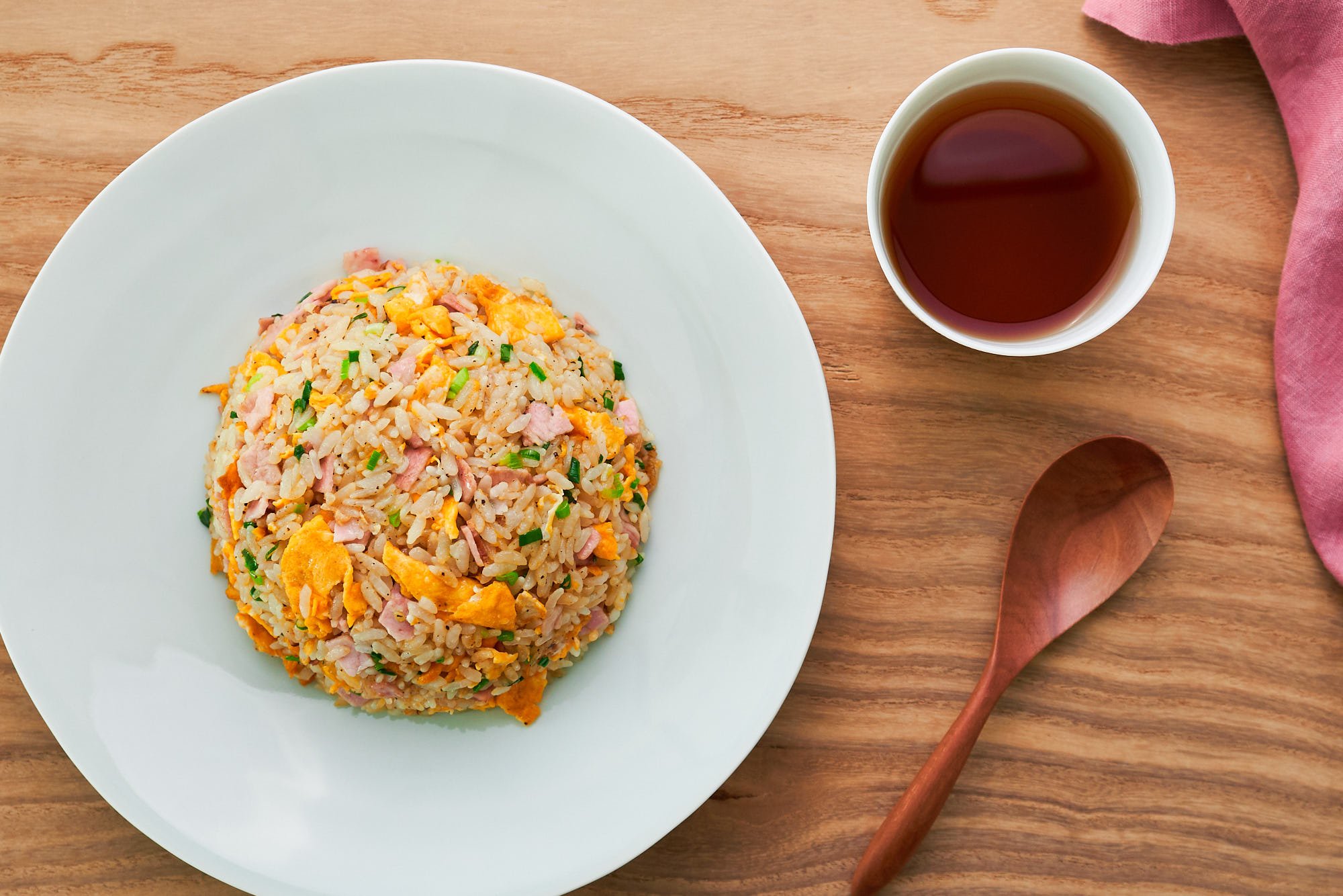 Yakimeshi (Japanese fried rice) on a white plate with barley tea and a wooden spoon.