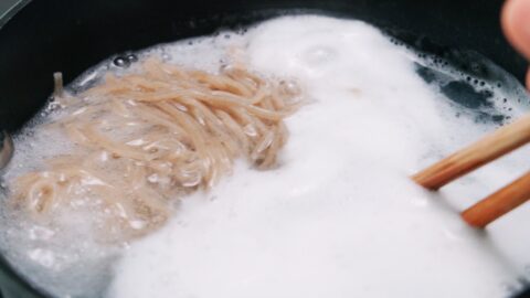 A pot of boiling water with soba noodles.